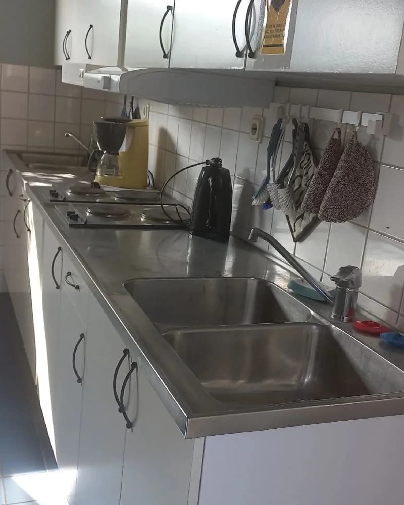 Ett modernt kök med diskbänk, kran och vitvaror, inrett med en stilren köksbänk och apparater.