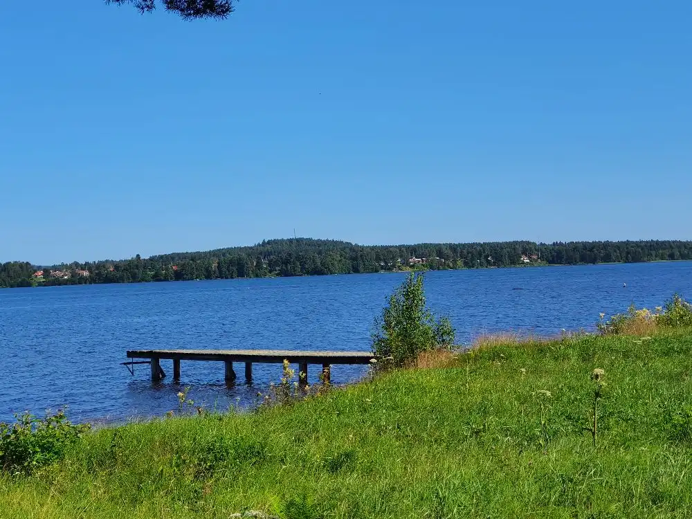 Alt-text: Vy över Västanviksbadets camping i Leksand med en klar blå sjö och omgivande naturlandskap.