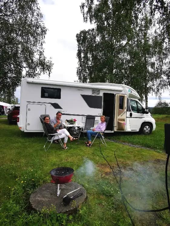 En grön gräsmatta med flera husvagnar och husbilar uppställda på en campingplats.