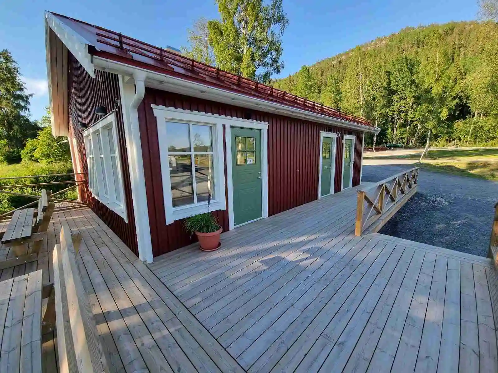 Bild av en trästuga vid Gällstasjön, omgiven av frodig natur. Stugan har en rymlig träveranda och är byggd av robusta träplankor. Perfekt för avkoppling och naturnära besök.