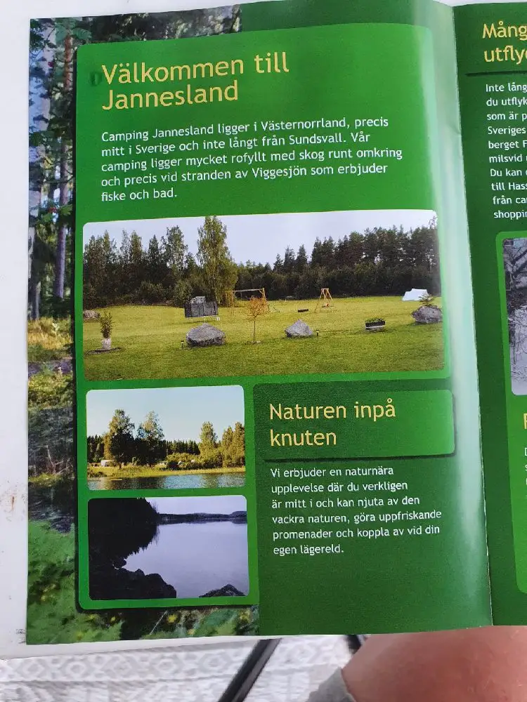 En reklamplansch för Camping Jannesland, omgiven av en grönskande bakgrund med inslag av våtmark.