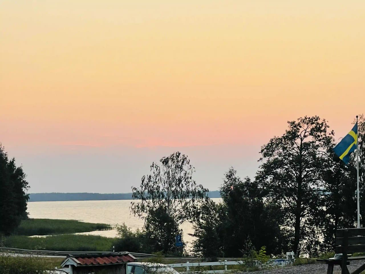 En solnedgång över Hjälmaresunds camping med horisont vid kusten, himlen skiftar i kvällsljusets varma färger.