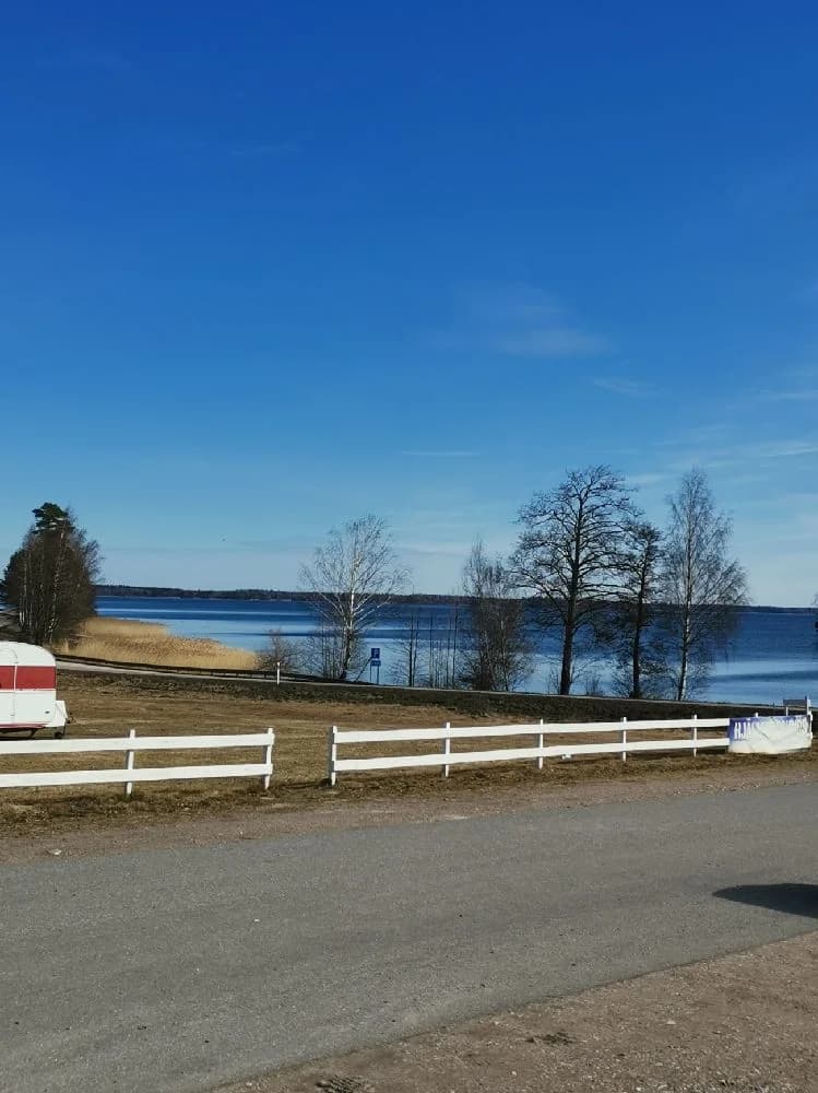 En campingplats med ett staket som markerar området, omgiven av grönska.