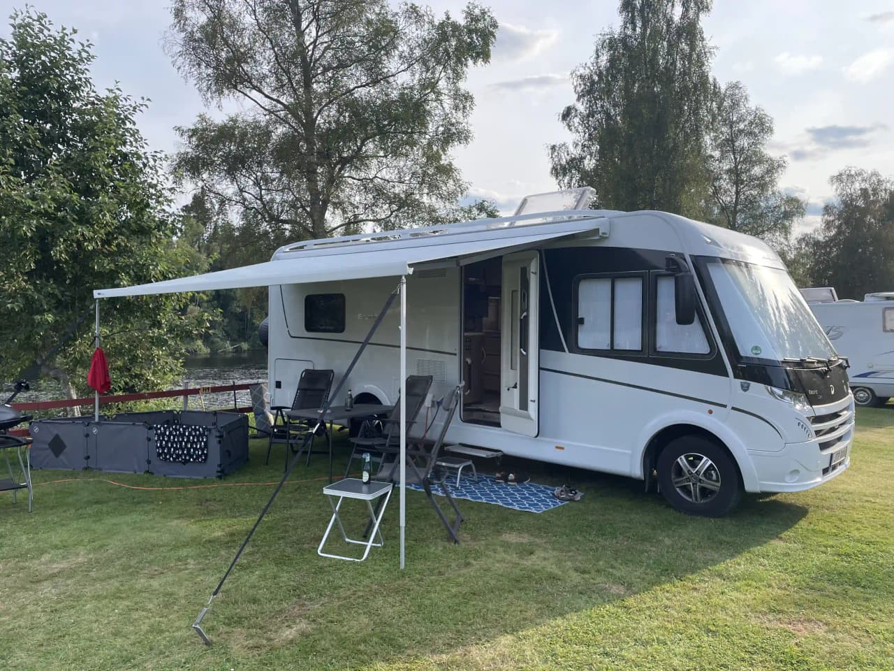 En campingplats vid Grebbestadfjorden med flera husvagnar och husbilar parkerade under en klar himmel. Några av fordonen har uppfällda markiser och området verkar vara populärt bland campingentusiaster.