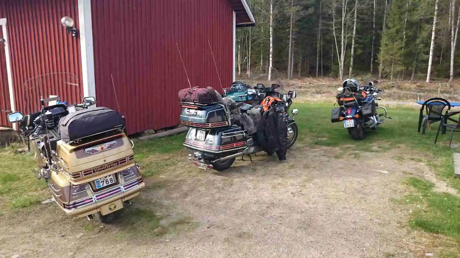 En motorcykel parkerad vid Höljes Camping, omgiven av skog och grönska.