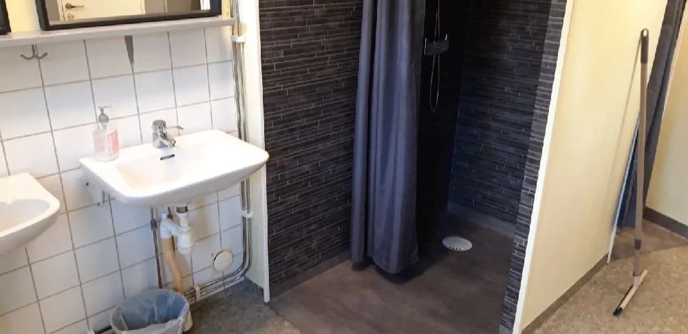 Ett badrum med modernt klinkergolv, en toalett, ett handfat och ljusa väggar på Björkebo camping.