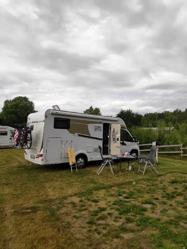 En campingplats med flera husvagnar och husbilar uppställda bland träd och grönska.