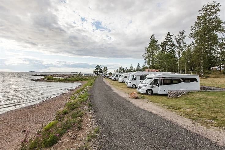 En husbil och en skåpbil parkerade nära kusten vid Askeviks Camping & Stugor, med havet i bakgrunden.