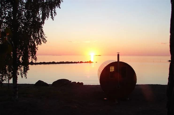 Solnedgång över havet vid Askeviks camping & stugor, med ett mjukt orange sken som färgar himlen och horisonten.