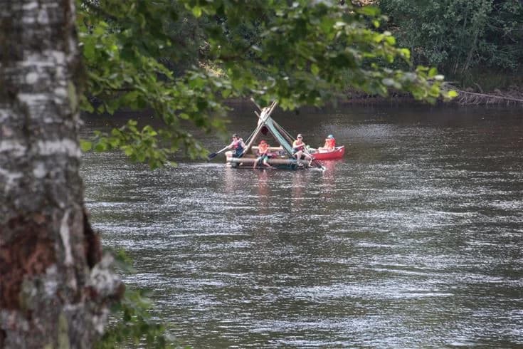 En båt ligger förtöjd vid en lugn flodbank på Björkebo Camping, omgiven av grönska och en klar vattenväg, perfekt för rekreation och friluftsliv.