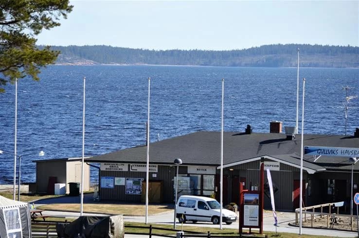 En liten flytbrygga som sträcker sig ut i vattnet vid Gullviks Havsbad Camping & Stugby, omgiven av en lugn och idyllisk miljö.