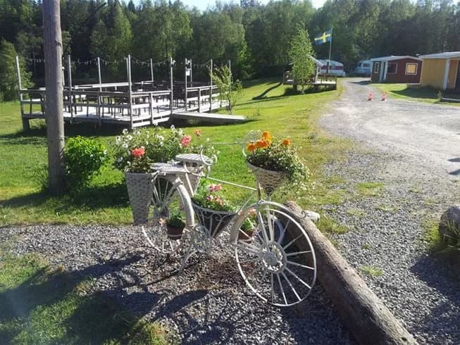 En cykel står parkerad på en grön gräsmatta vid Antjärns camping, omgiven av lummig grönska och en fridfull miljö.