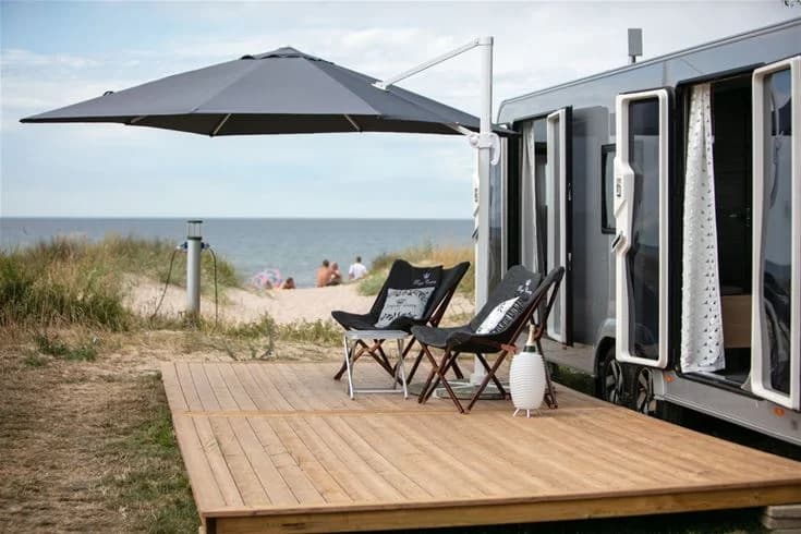 En avkopplande uteplats på Tofta Camping med skuggiga områden och bekväma utemöbler på ett trädäck.