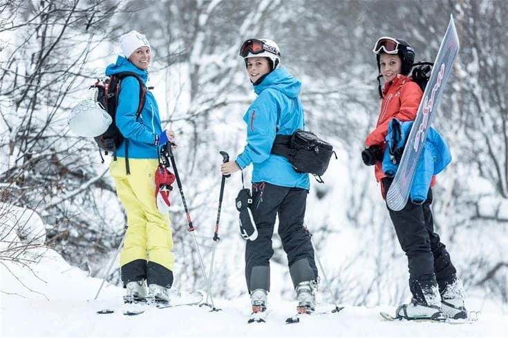 En person klädd i vinterkläder och ryggsäck står i ett snöigt landskap vid Bjursås Berg & Sjö, redo för vintersportaktiviteter.