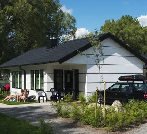 En stuga med grönmålade väggar omgiven av en välskött gräsmatta på Gustavsvik Resort.