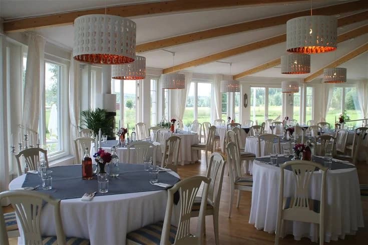 En utomhusbild från Degernäs camping visar en grönskande gräsmatta med trädgårdsmöbler inklusive ett bord täckt med en rutig duk och flera stolar, allt i en trivsam utomhusmiljö.