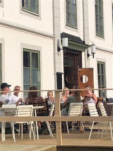 En öppen utomhusrestaurang vid Degernäs Camping med bord och stolar i en naturskön miljö.