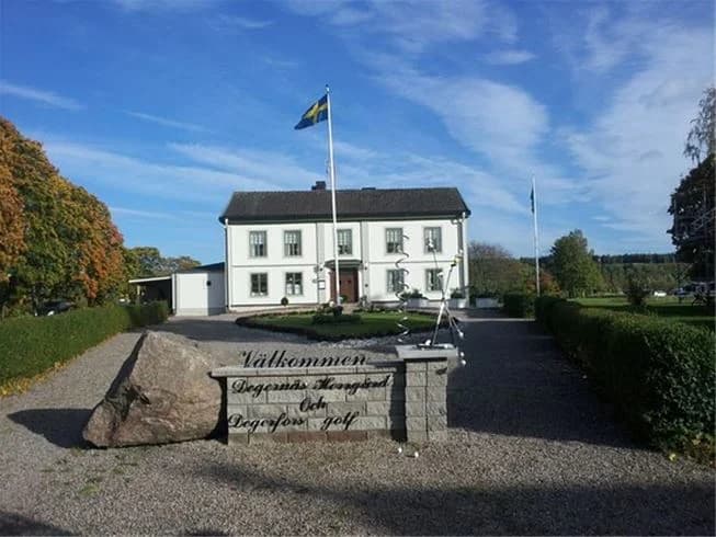 En stuga omgiven av grönskande gräsmatta och landskapsarkitektur på Degernäs camping.