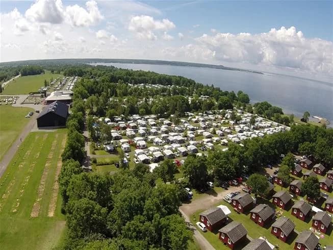 Fågelperspektiv över Lundegård Camping & Stugby och dess närliggande kustlinje. Bilden visar campingens utformning i relation till havet och den omgivande naturen, vilket framhäver platsens attraktiva läge vid kusten.