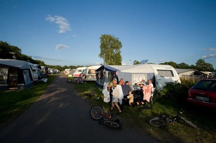 Bild av Lundegård Camping & Stugby som visar en campingplats med uppställda husvagnar och husbilar, omgiven av grönska. Perfekt för en avkopplande semester.