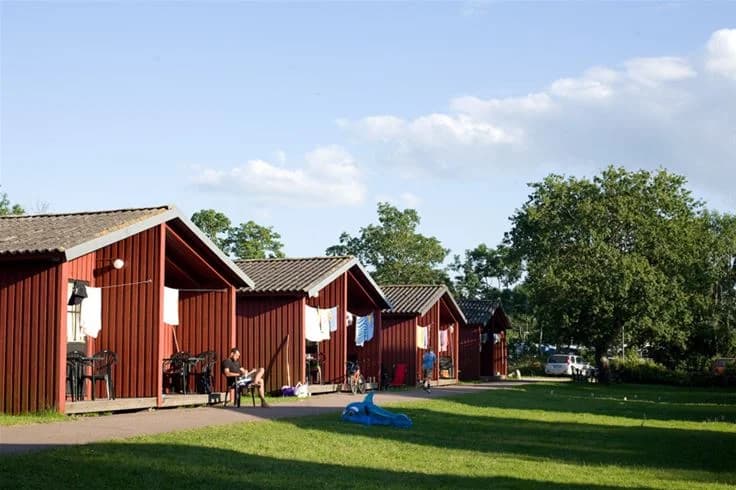 En grönskande campingplats med välskötta gräsmattor, där besökare njuter av fritidsaktiviteter i en parkmiljö.