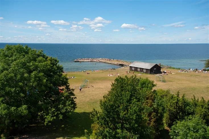 Bild av en somrig kust vid Lundegård Camping & Stugby med utsikt över havet, sandstrand och horisont.