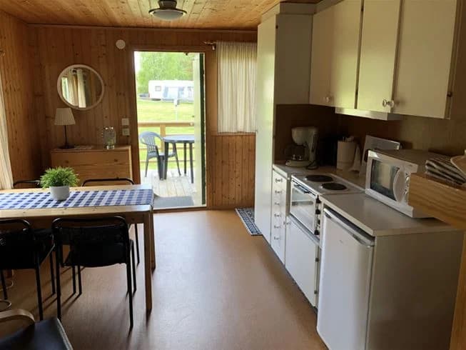 En träinredd interiör med trämöbler, inklusive stolar och ett köksbord, på Malexander Camping. Golvet är av trä, vilket bidrar till den naturliga och rustika känslan av lokalen.