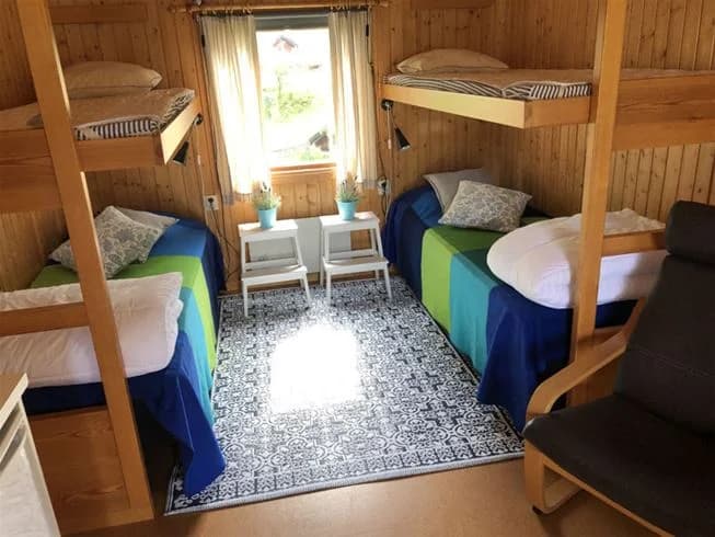 En träinteriör av en sovstuga på Malexander camping, med våningssängar, trägolv och enkel möblering.