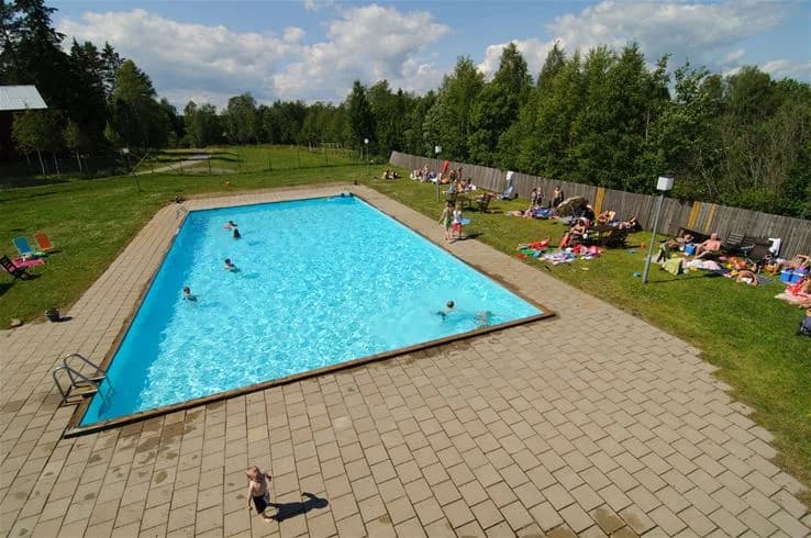 En pool på Lufta Camping & Restaurang med människor som simmar och njuter av sin semester i en avslappnad och rolig miljö.