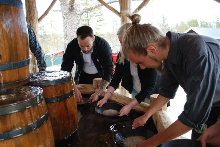 Ett rustikt kök med trätunnor och tunnor uppställda mot väggen. I förgrunden hänger en jacka på en krok. Atmosfären är varm och inbjudande, vilket ger en känsla av en liten, hemtrevlig restaurang på Lufta Camping.