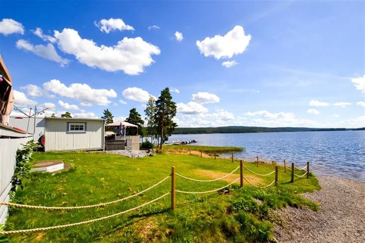 En naturskön campingplats belägen vid en sjö med grönskande gräsmattor och en lugn strandkant.