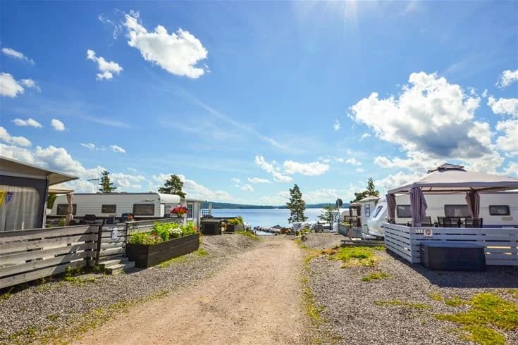Bild av Charlottenberg camping & stugor - Haganäset, med en kustlinje vid havet, husvagnar parkerade längs stranden under en himmel med moln.