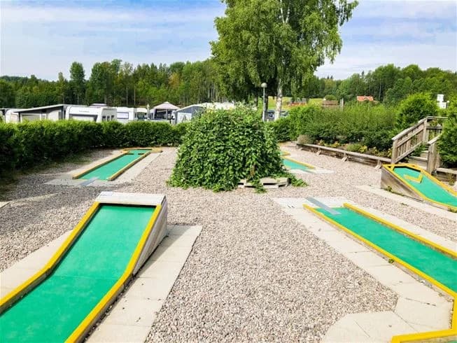 En grön och välskött minigolfbana med konstgräs på Charlottenberg camping & stugor - Haganäset, omgiven av lummig natur. Perfekt för en familjeutflykt eller avkopplande fritidsaktivitet.