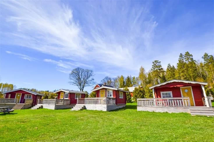 En mysig stuga i en naturskön miljö vid Charlottenberg camping & stugor - Haganäset, omgiven av grönskande gräsmattor och vacker landskapsarkitektur.