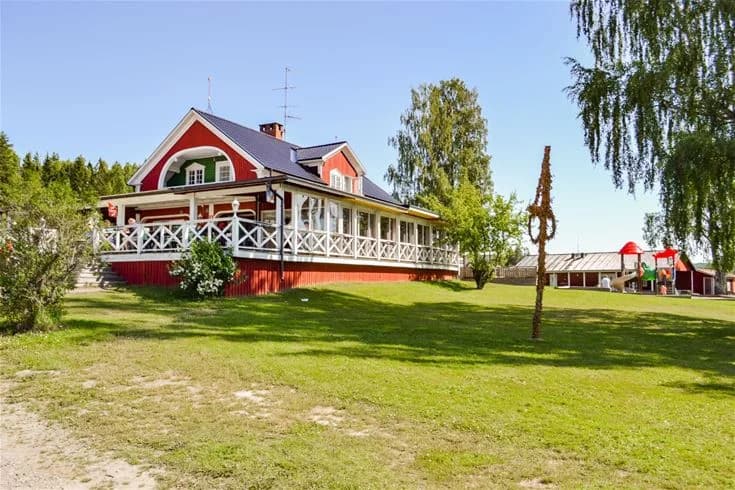 En lantlig fastighet med en gårdsliknande byggnad omgiven av grönska på Charlottenberg camping & stugor - Haganäset.