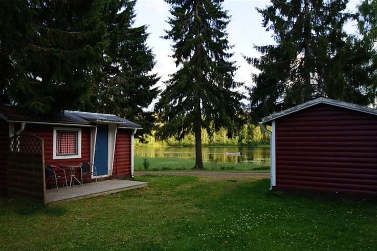 En pittoresk stuga ligger omgiven av frodig grönska och träd på Stöde Camping. En välskött gräsmatta och trädgård bidrar till platsens natursköna atmosfär.
