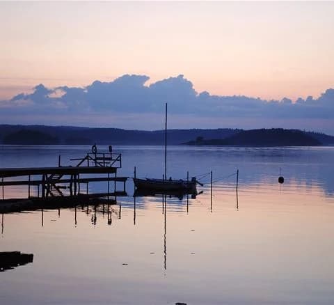 En stilla sjö vid Anfasteröd Gårdsvik i skymningsljus, med horisonten svagt upplyst av efterglöden.