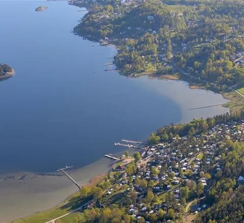 Flygfoto över Anfasteröd Gårdsvik, med en stor vattenresurs i förgrunden. Bilden visar kustlinjer och landformationer kring en sjö eller kanal.