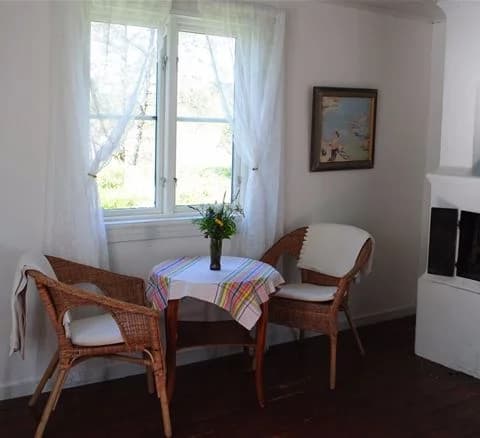 Ett mysigt rum på Anfasteröd Gårdsvik med träinredning, möblerat med stolar och bord på ett trägolv samt varm belysning.