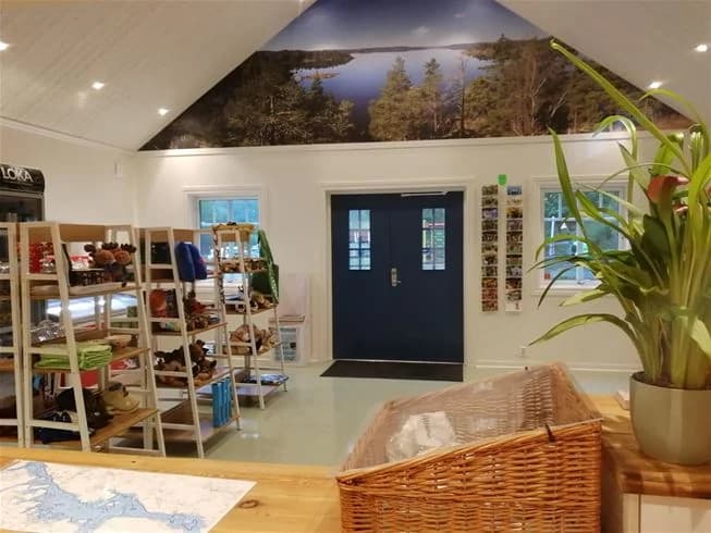 Ett modernt och välkomnande rum på Yxningens camping, med träinredning och ljusa golv. Takkonstruktionen är synlig, och rummet är möblerat med hyllor och andra praktiska möbler. Belysningen skapar en varm atmosfär.