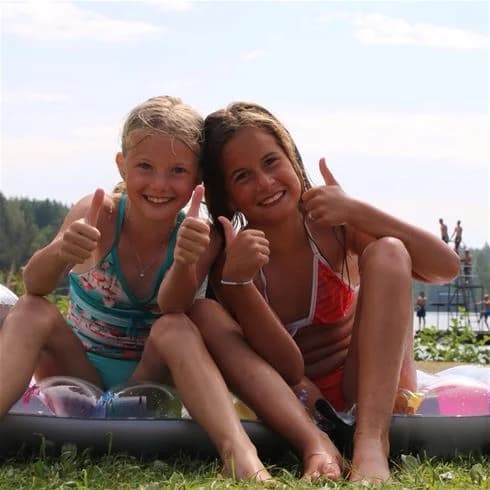 En grupp glada människor som sitter och njuter av sommaren vid Yxningens camping, omgivna av grönska och skön atmosfär.