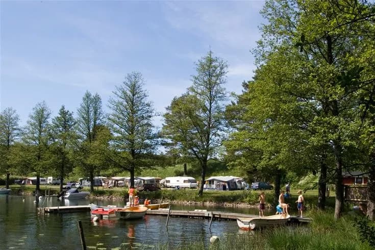 En sjö vid Yxningens camping, med en båt förtöjd vid strandkanten och omgivande naturlandskap, perfekt för rekreation och naturupplevelser.