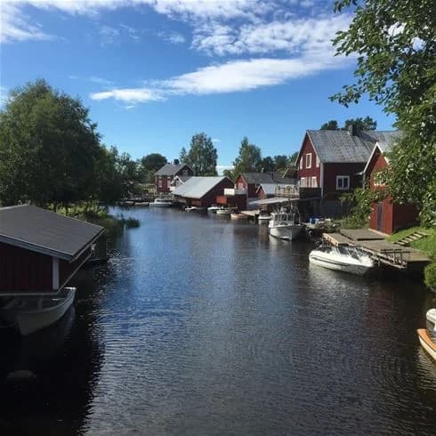En båt glider längs en lugn vattenväg nära Sörfjärdens camping, omgiven av frodig natur och en stilla kanal. Perfekt utflyktsmål för natursköna båtturer.