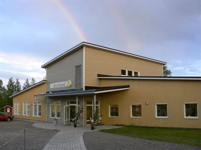 En trevlig och inbjudande byggnad, typisk för ett kursgårdscenter, med en lantlig känsla och omgiven av grönska. 
