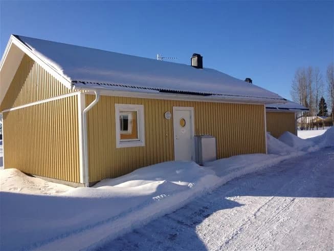 En vinterbild av Storstrand kursgård, med ett snötäckt tak och träfasad. Området är insvept i snö, vilket skapar en fridfull och kall vinteratmosfär.