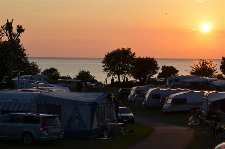 En vacker kustlinje med sandstrand och tält uppställda nära havet vid Klinta Camping, ett populärt semestermål vid kusten.