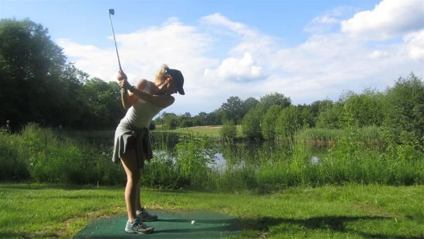 En person spelar golf på en grön campingområde vid Dalskärs Camping, omgiven av golfutrustning och gräsmark för utomhusrekreation.