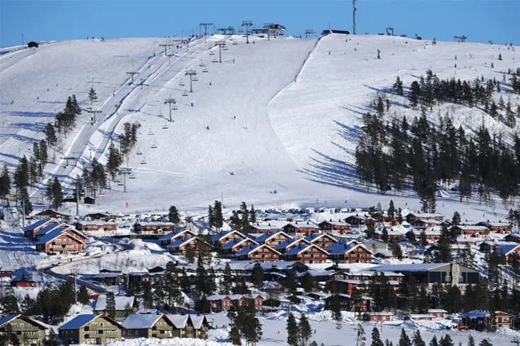 Bild av Idre Fjäll Camping i vinterskrud med snötäckta berg och backar. En fridfull vinterdestination med frostiga landskap och skidmöjligheter.