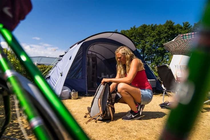 En härlig sommardag på Haga Park Camping & Stugor med tält uppställda bland grönska, människor njuter av fritid och rekreation utomhus.