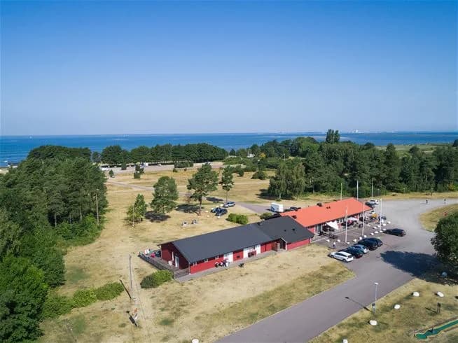 Flygbild över Haga Park Camping & Stugor, som visar en lummig campingplats med skuggiga områden, stugor och rekreationsytor.